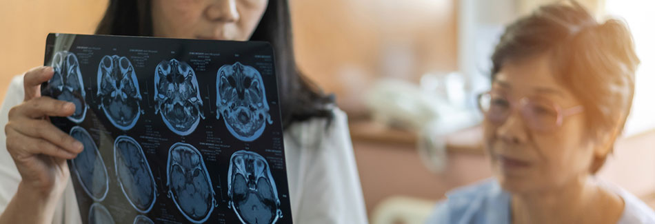 Medical doctor diagnosing an elderly patient with brain cancer by reviewing an MRI film.